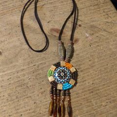 This is a bohemian-style long necklace featuring a resin pendant and beaded tassels.