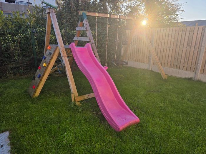 Wooden climbing frame with slide and swings