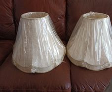 A pair of cream coloured lamp shades still in wrapping