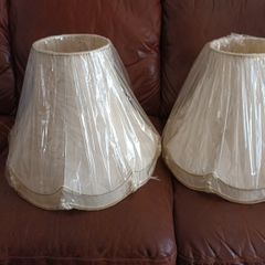 A pair of cream coloured lamp shades still in wrapping