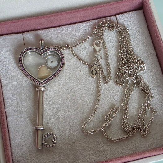 Pandora sterling silver key necklace with a heart,shaped floating locket and pink sparkling stones. Includes the two petite charms