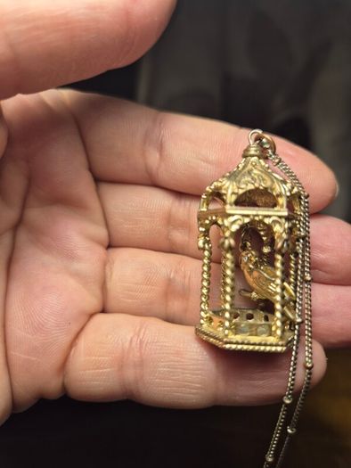 Vintage gilded bird cage with a bird pendant.