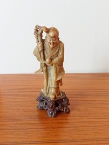 Hand-carved Chinese soapstone statue of Shou Lao the Taoist God of Longevity resting on a separate dark stone pedestal  early 20th century  height 15.5cm