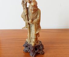 Hand-carved Chinese soapstone statue of Shou Lao the Taoist God of Longevity resting on a separate dark stone pedestal  early 20th century  height 15.5cm