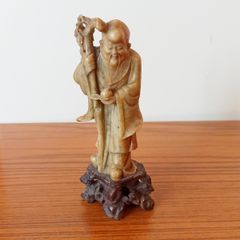 Hand-carved Chinese soapstone statue of Shou Lao the Taoist God of Longevity resting on a separate dark stone pedestal  early 20th century  height 15.5cm