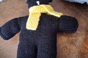 Hand knitted black teddy bear with yellow scarf
