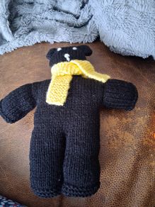 Hand knitted black teddy bear with yellow scarf