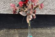 Tall glass vase containing artificial flower arrangement