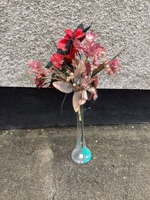 Tall glass vase containing artificial flower arrangement