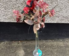 Tall glass vase containing artificial flower arrangement