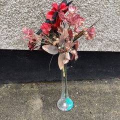 Tall glass vase containing artificial flower arrangement