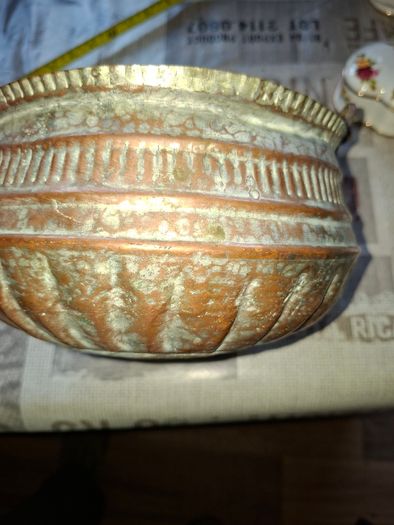 Antique Copper Cauldron features a Rustic Patina, a Swing Handle, and Distinctive Ribbed Detailing around the Rim. It resembles vintage metal pots often used for hearth decoration or as Planters. The piece shows significant oxidation and aging, characteri
