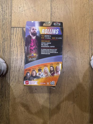 The item shown is the WWE Elite Collection Series 86 SummerSlam Seth Rollins action figure by Mattel, featuring his pink and black ring gear, TrueFX facial detailing, and themed accessories.