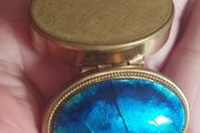 A vintage metal pill box with an enamel lid.