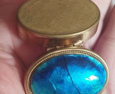 A vintage metal pill box with an enamel lid.
