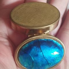A vintage metal pill box with an enamel lid.