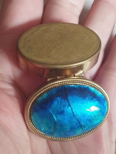 A vintage metal pill box with an enamel lid.