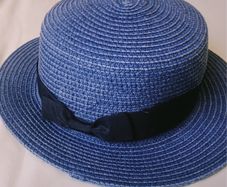 Blue woven straw boater hat with black ribbon bow, lightweight and excellent condition.
