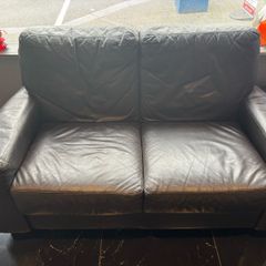 pre-owned black leather two-seater sofa with plump back cushions and wide arms.