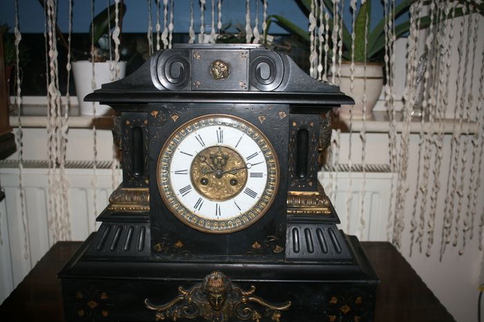 Victorian French Black Slate Mantle Clock (Very large and heavy) with bronze ornamentation Oversized. Open escarpment slate plate Roman numerals. Circa 1890s. Accented with Trojan head. Flanked by two Hellenistic ladies heads on sides. Rose cartouche mask