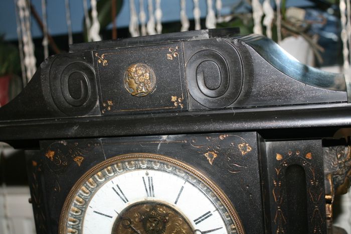 Victorian French Black Slate Mantle Clock (Very large and heavy) with bronze ornamentation Oversized. Open escarpment slate plate Roman numerals. Circa 1890s. Accented with Trojan head. Flanked by two Hellenistic ladies heads on sides. Rose cartouche mask
