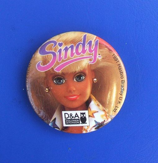DOLLOND & AITCHISON (high-street opticians) - a promotional button badge featuring a Sindy doll (1990s)