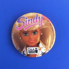 DOLLOND & AITCHISON (high-street opticians) - a promotional button badge featuring a Sindy doll (1990s)