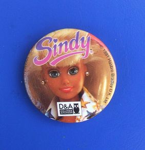 DOLLOND & AITCHISON (high-street opticians) - a promotional button badge featuring a Sindy doll (1990s)