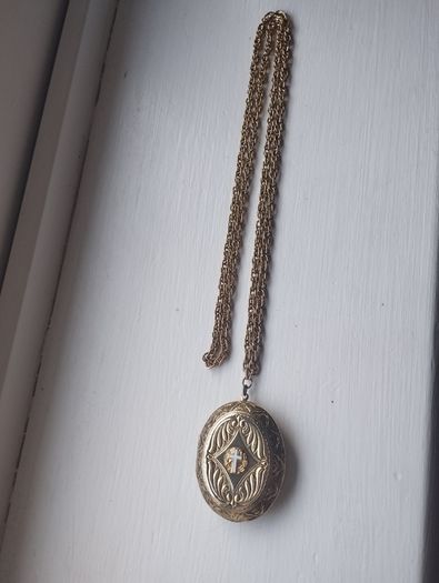 A large medallion featuring religious symbols, suspended from a long chain.