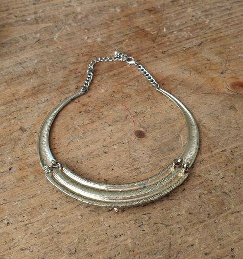 choker necklace. It combines a rigid metallic collar band with an intricately layered bohemian bib display.