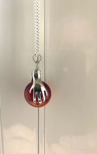Silver tone necklace with unique hand-clasp pendant