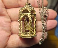 Vintage gilded bird cage with a bird pendant.