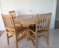 solid pine pedestal dining table with 4 matching four slatted wooden chairs.