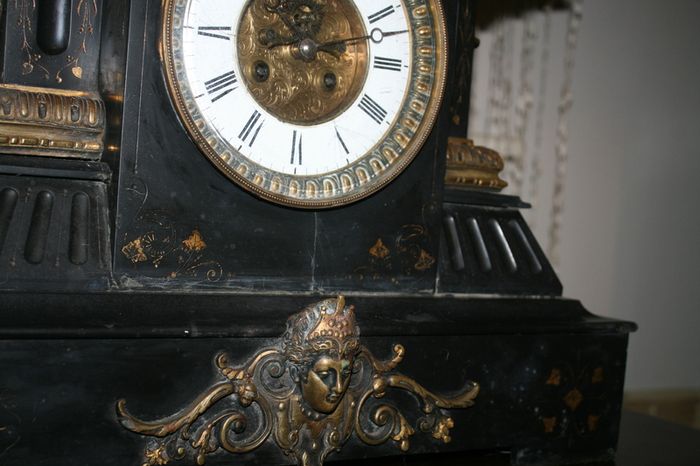 Victorian French Black Slate Mantle Clock (Very large and heavy) with bronze ornamentation Oversized. Open escarpment slate plate Roman numerals. Circa 1890s. Accented with Trojan head. Flanked by two Hellenistic ladies heads on sides. Rose cartouche mask
