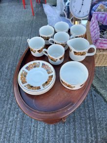 The set shown is a 1970s Arklow Pottery "Studio Kraft" tea/coffee set manufactured in County Wicklow, Ireland. It features a classic 1970s mid-century retro floral pattern in amber, orange, and brown tones with gold trim