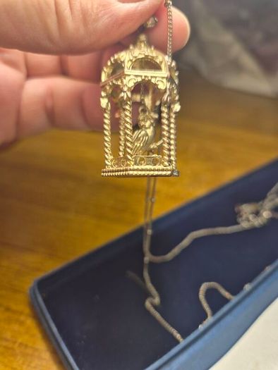 Vintage gilded bird cage with a bird pendant.