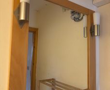 This pine-framed mirror includes two attached wall sconces for lighting.