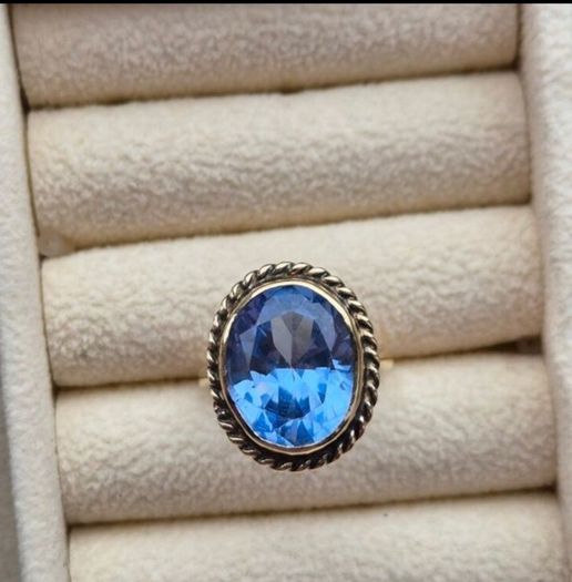 Beautiful 9K gold ring featuring a stunning large oval blue stone.