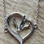 A silver bracelet with a heart-shaped pendant featuring a horse and foal's head. Image 7