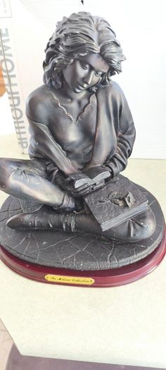 Bronze-toned sculpture of a woman reading, often titled -Reading Time Girl-  produced by The Milano Collection