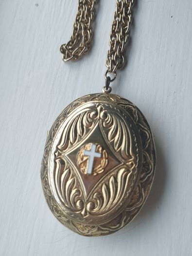 A large medallion featuring religious symbols, suspended from a long chain.