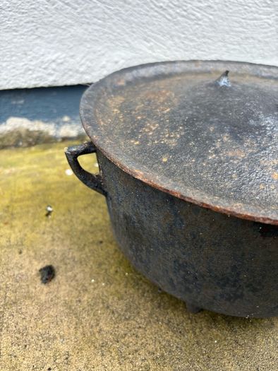 Antique cast iron tri-legged dutch oven and lid.