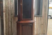 A tall mahogany corner cabinet.