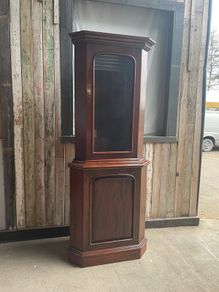 A tall mahogany corner cabinet.