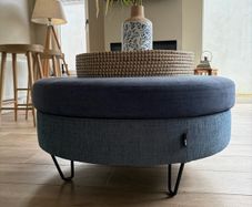 Large Round Blue Ottoman / Footstool with Storage  Stylish round ottoman with a dark denim-blue cushioned top, textured lighter blue base and black metal legs.  The top lifts off to reveal a handy storage space. Perfect as a footstool or styled with a tra