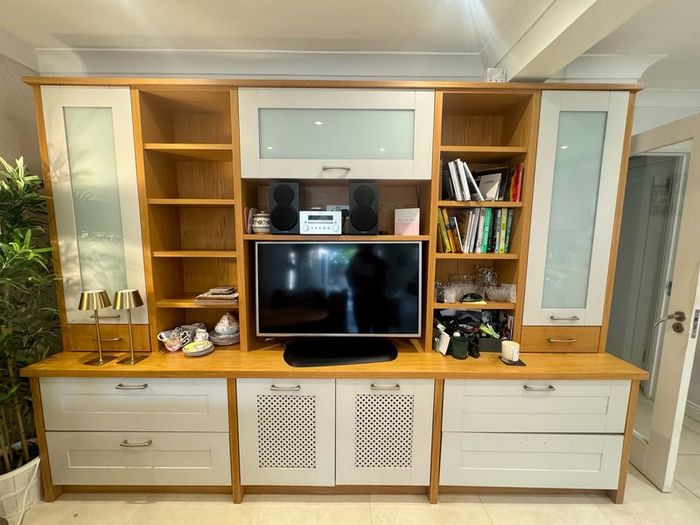 large wooden entertainment center or wall unit featuring a mix of open shelving, glass fronted cabinets, and lower drawers