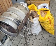 This handmade stainless steel grill features a stainless steel base and 6 bags of firewood.