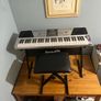 RockJam Electronic Keyboard Piano set up on a sturdy, matching heavy-duty Z-frame stand and an adjustable padded X-frame RockJam Keyboard Bench resting on a wooden surface. Image 3