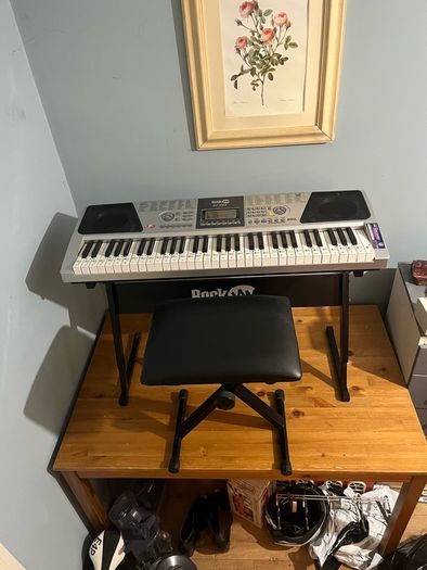 RockJam Electronic Keyboard Piano set up on a sturdy, matching heavy-duty Z-frame stand and an adjustable padded X-frame RockJam Keyboard Bench resting on a wooden surface.