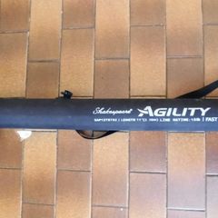 Shakespeare Agility Spin fishing rod. 11 feet (3.30 meters) in length. The item includes a black carrying tube with a strap for transport.